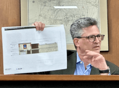Great Neck Plaza Trustee Lawrence Katz holds up a facade rendering for the new Aldi coming to the village
